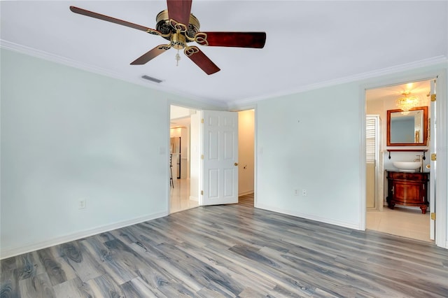 unfurnished bedroom with ornamental molding, connected bathroom, wood-type flooring, sink, and ceiling fan