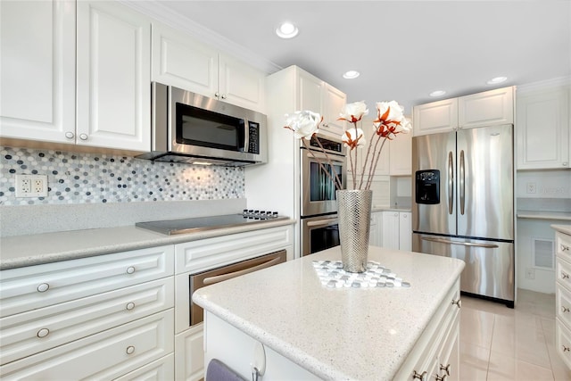 kitchen with appliances with stainless steel finishes, tasteful backsplash, a center island, and white cabinets