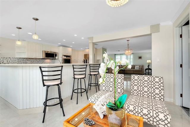 interior space with backsplash, light tile patterned floors, stainless steel appliances, kitchen peninsula, and a breakfast bar area