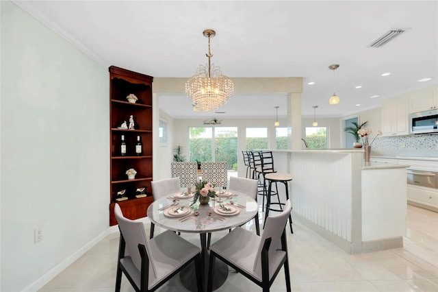 dining space featuring ornamental molding, an inviting chandelier, and light tile patterned floors