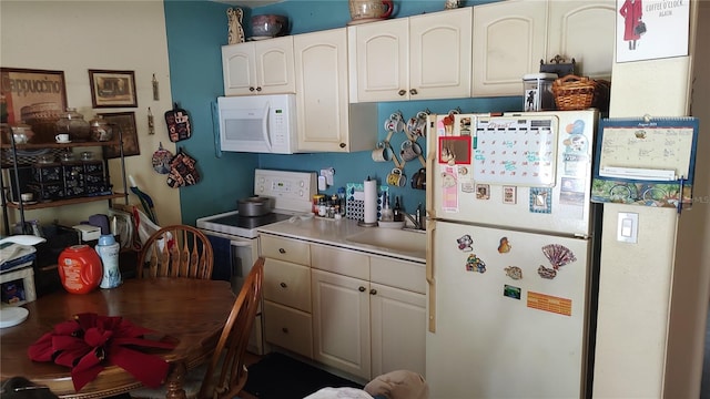 kitchen featuring white cabinetry, sink, and white appliances