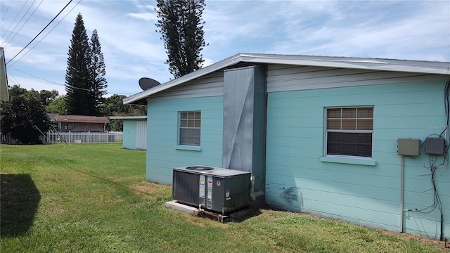 view of side of home featuring central air condition unit and a yard