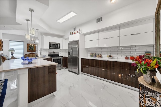 kitchen with stainless steel appliances, decorative backsplash, white cabinetry, light tile patterned flooring, and hanging light fixtures