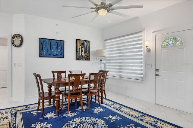 dining room featuring baseboards, marble finish floor, a ceiling fan, and a healthy amount of sunlight