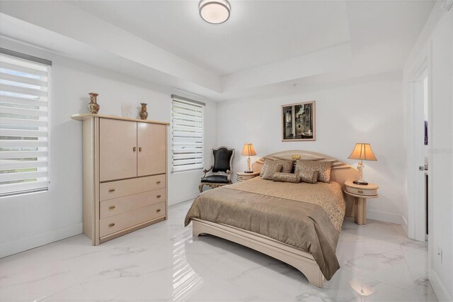 bedroom with a raised ceiling and light tile patterned floors