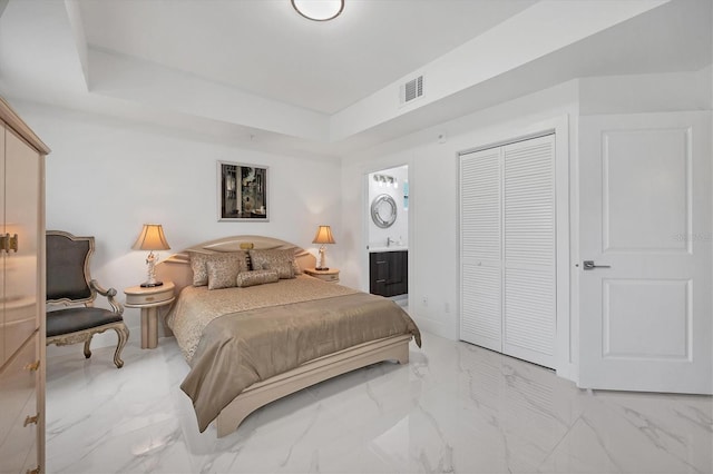 bedroom with connected bathroom, a raised ceiling, and light tile patterned floors