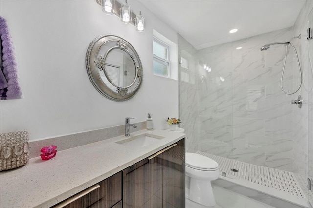 bathroom with vanity, tiled shower, and toilet