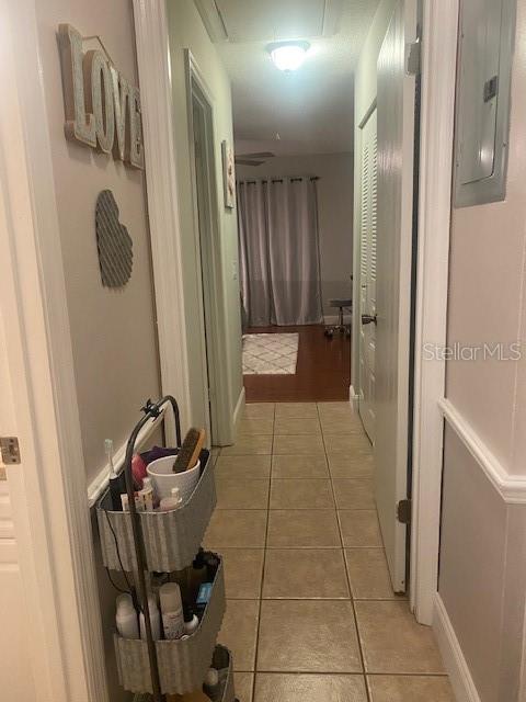 corridor with light tile patterned flooring and electric panel