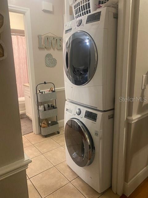 laundry area featuring light tile patterned flooring and stacked washer and dryer