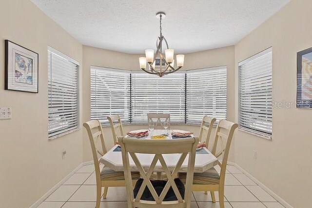 tiled dining room featuring a textured ceiling, an inviting chandelier, and a healthy amount of sunlight