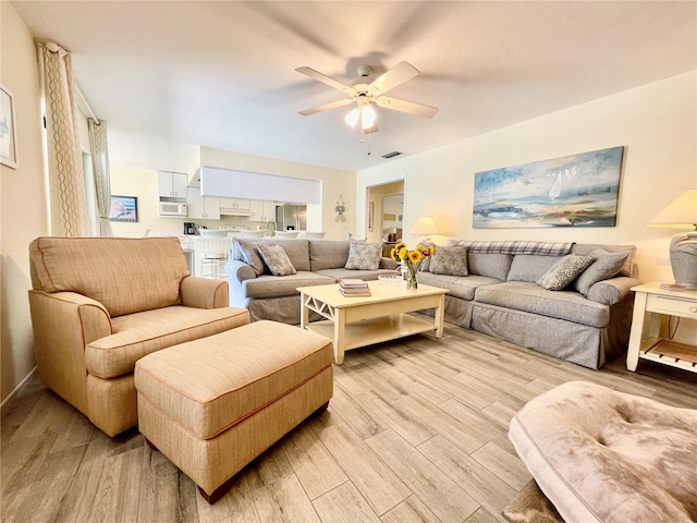 living room featuring light wood-type flooring, ceiling fan, and sink