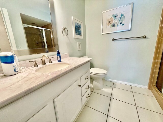 bathroom with tile patterned flooring, vanity, toilet, and walk in shower