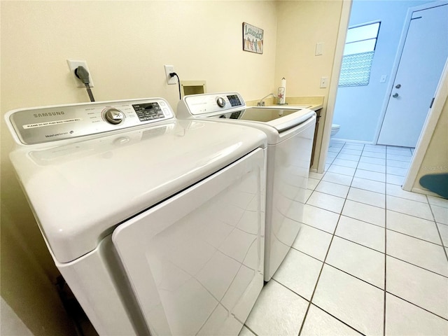 washroom featuring washing machine and dryer, sink, and light tile patterned floors