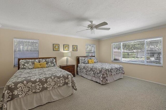 carpeted bedroom with ceiling fan, ornamental molding, and a textured ceiling