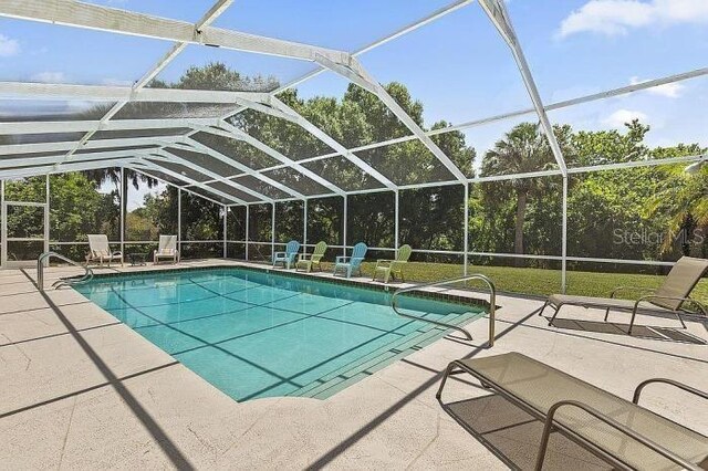 view of swimming pool featuring glass enclosure and a patio