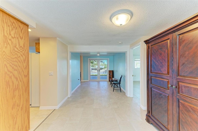 hall with french doors and a textured ceiling