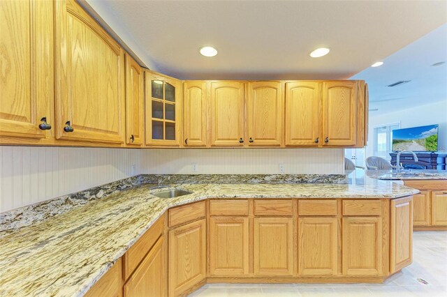 kitchen with sink, light stone countertops, and kitchen peninsula