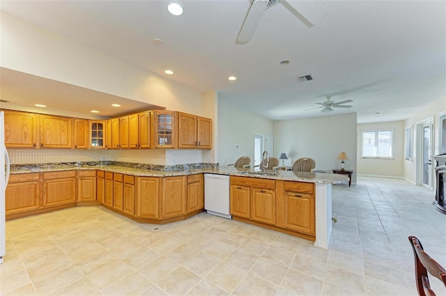 kitchen featuring kitchen peninsula, sink, white dishwasher, ceiling fan, and light stone counters