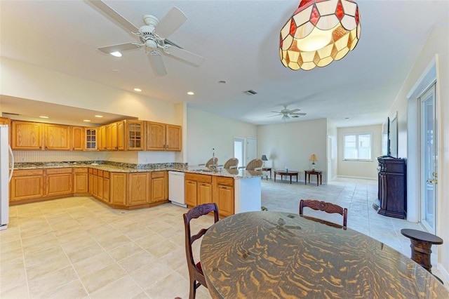 kitchen with kitchen peninsula, light stone countertops, sink, white appliances, and ceiling fan