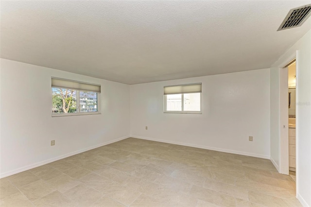 spare room featuring a textured ceiling and a healthy amount of sunlight