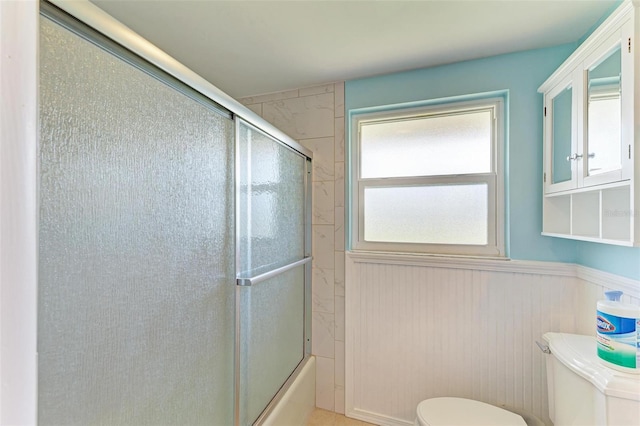 bathroom featuring enclosed tub / shower combo and toilet