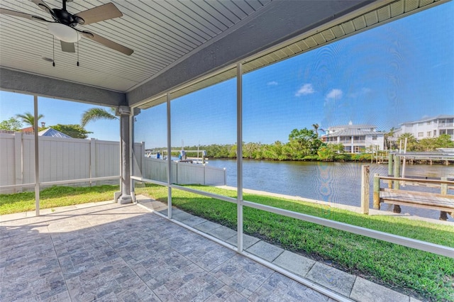 unfurnished sunroom featuring ceiling fan and a water view