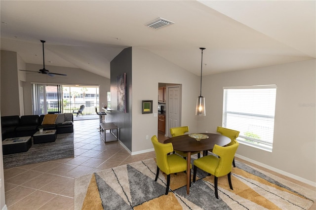 tiled dining space featuring ceiling fan, vaulted ceiling, and a healthy amount of sunlight