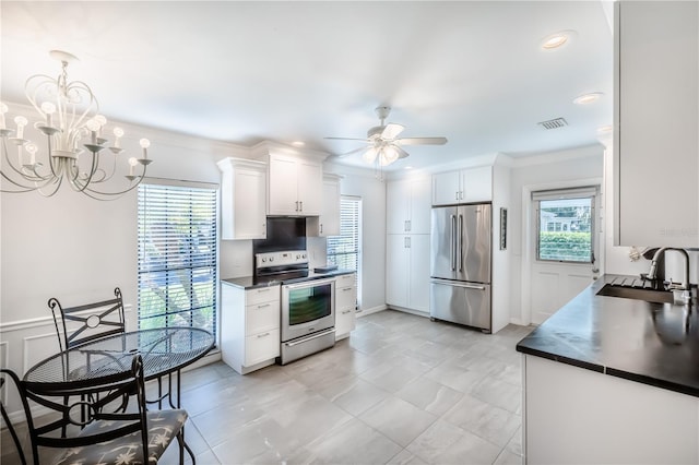 kitchen featuring ceiling fan with notable chandelier, plenty of natural light, stainless steel appliances, white cabinetry, and sink