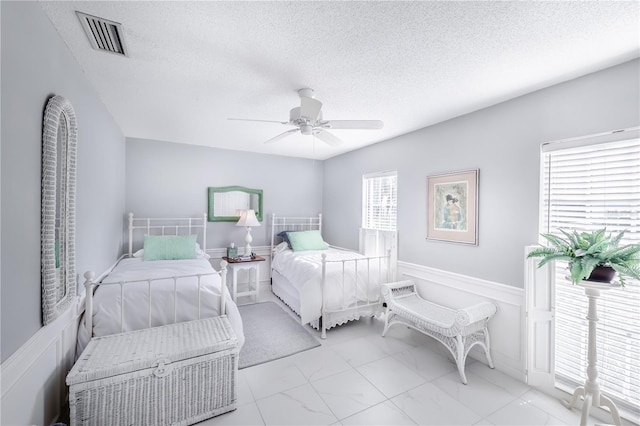 bedroom with ceiling fan and a textured ceiling