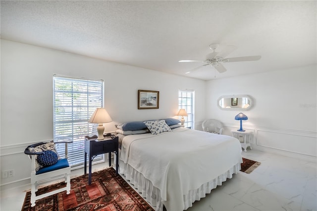 bedroom featuring a textured ceiling, ceiling fan, and multiple windows