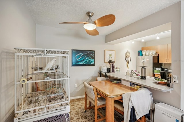 carpeted dining space featuring a textured ceiling, ceiling fan, and rail lighting