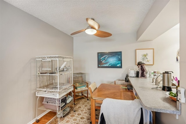 dining space featuring ceiling fan, light wood-type flooring, and a textured ceiling