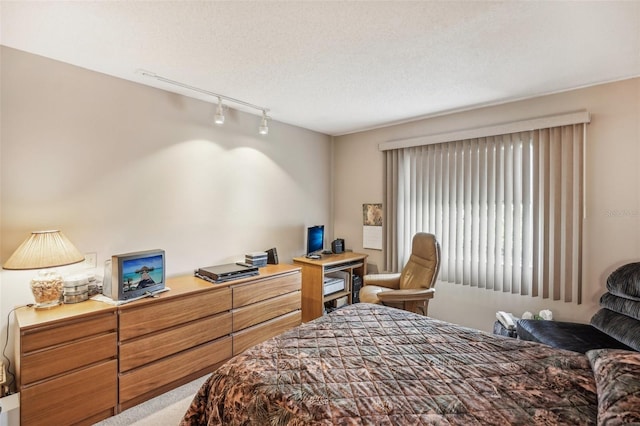 bedroom with carpet, a textured ceiling, and track lighting