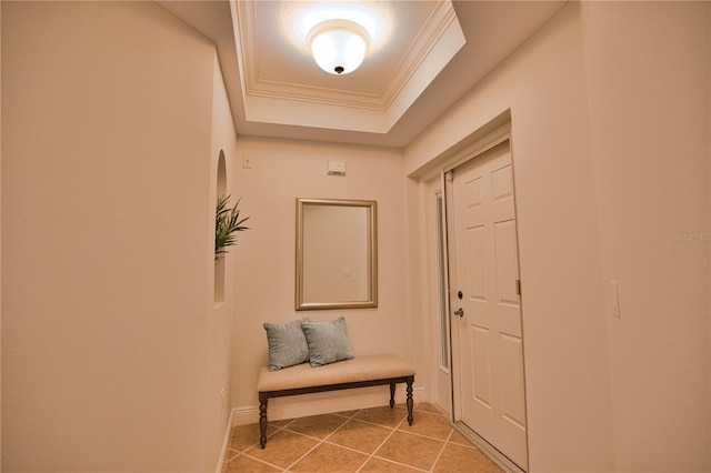 doorway featuring light tile patterned floors, a tray ceiling, ornamental molding, and baseboards