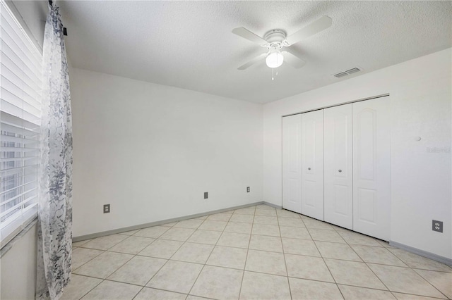 unfurnished bedroom featuring multiple windows, ceiling fan, and a textured ceiling