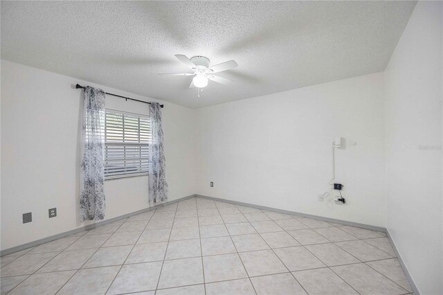 empty room with a textured ceiling, ceiling fan, and light tile patterned floors