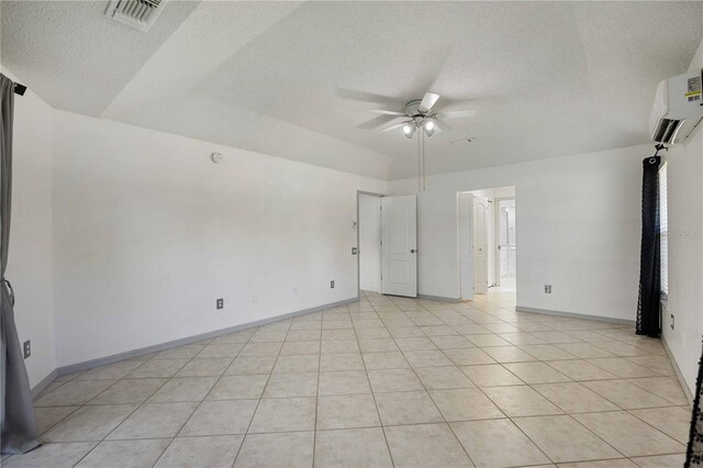 tiled empty room with a textured ceiling, ceiling fan, and a wall unit AC