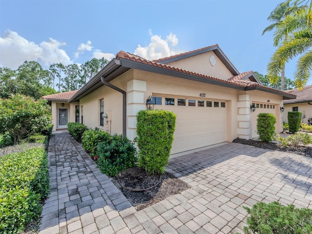 view of home's exterior featuring decorative driveway, a tiled roof, an attached garage, and stucco siding