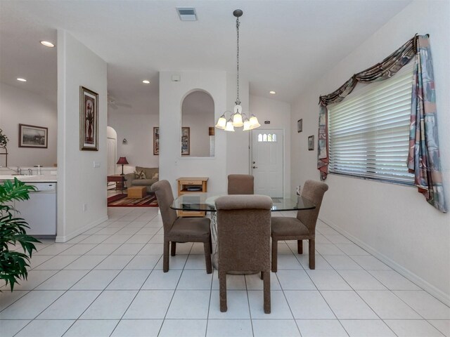 dining space with a chandelier, light tile patterned flooring, and vaulted ceiling