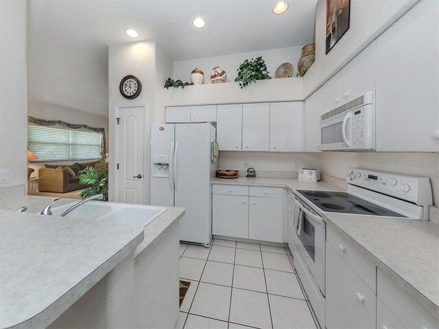 kitchen with sink, light tile patterned floors, white appliances, and white cabinets