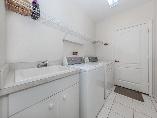 clothes washing area with washer and dryer, light tile patterned flooring, and sink