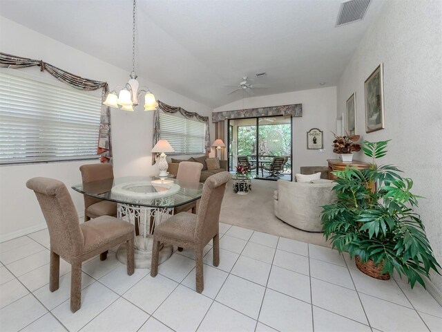 tiled dining area featuring ceiling fan with notable chandelier and lofted ceiling