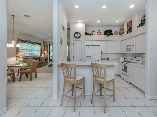 kitchen featuring a kitchen breakfast bar, white appliances, light tile patterned floors, kitchen peninsula, and white cabinets