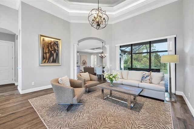 living room featuring a towering ceiling, ornamental molding, dark hardwood / wood-style flooring, and a chandelier