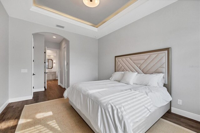 bedroom with a tray ceiling and dark hardwood / wood-style flooring