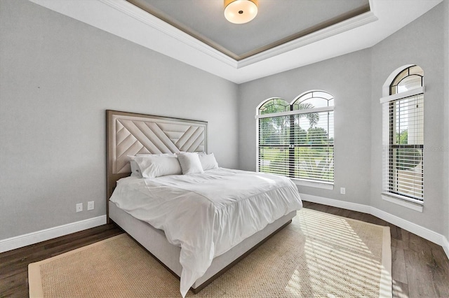 bedroom featuring ornamental molding, a raised ceiling, and dark wood-type flooring