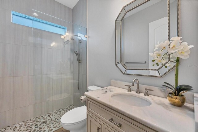 bathroom with vanity, toilet, and tiled shower