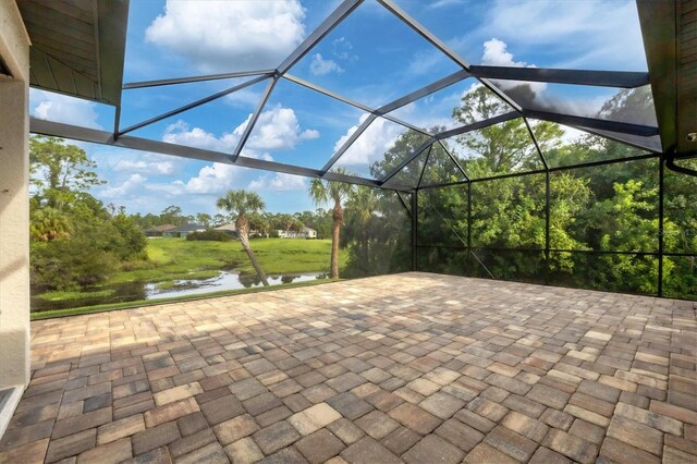 view of patio with glass enclosure and a water view