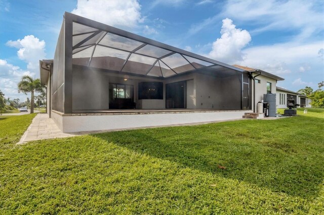 rear view of house with a lawn and glass enclosure