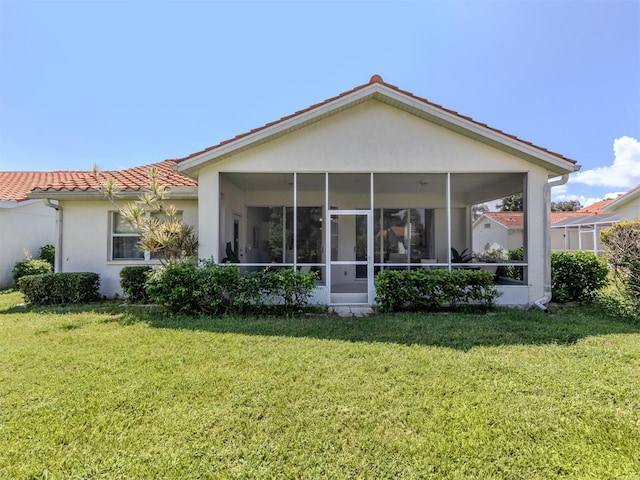 rear view of property featuring a yard and a sunroom